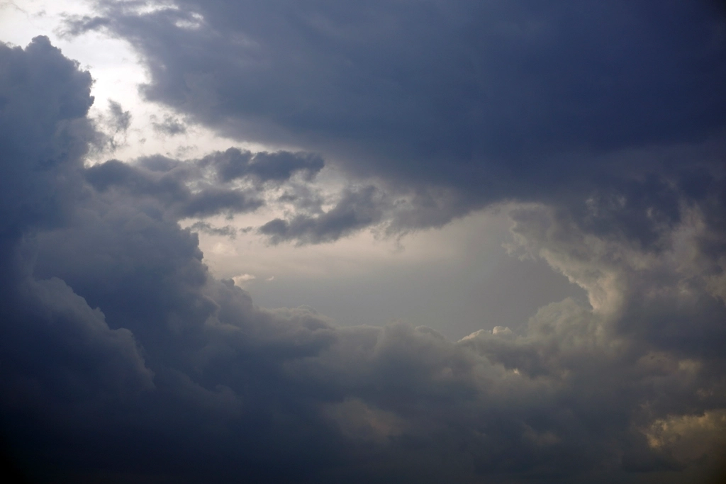 Dark storm clouds over open landscape with rain